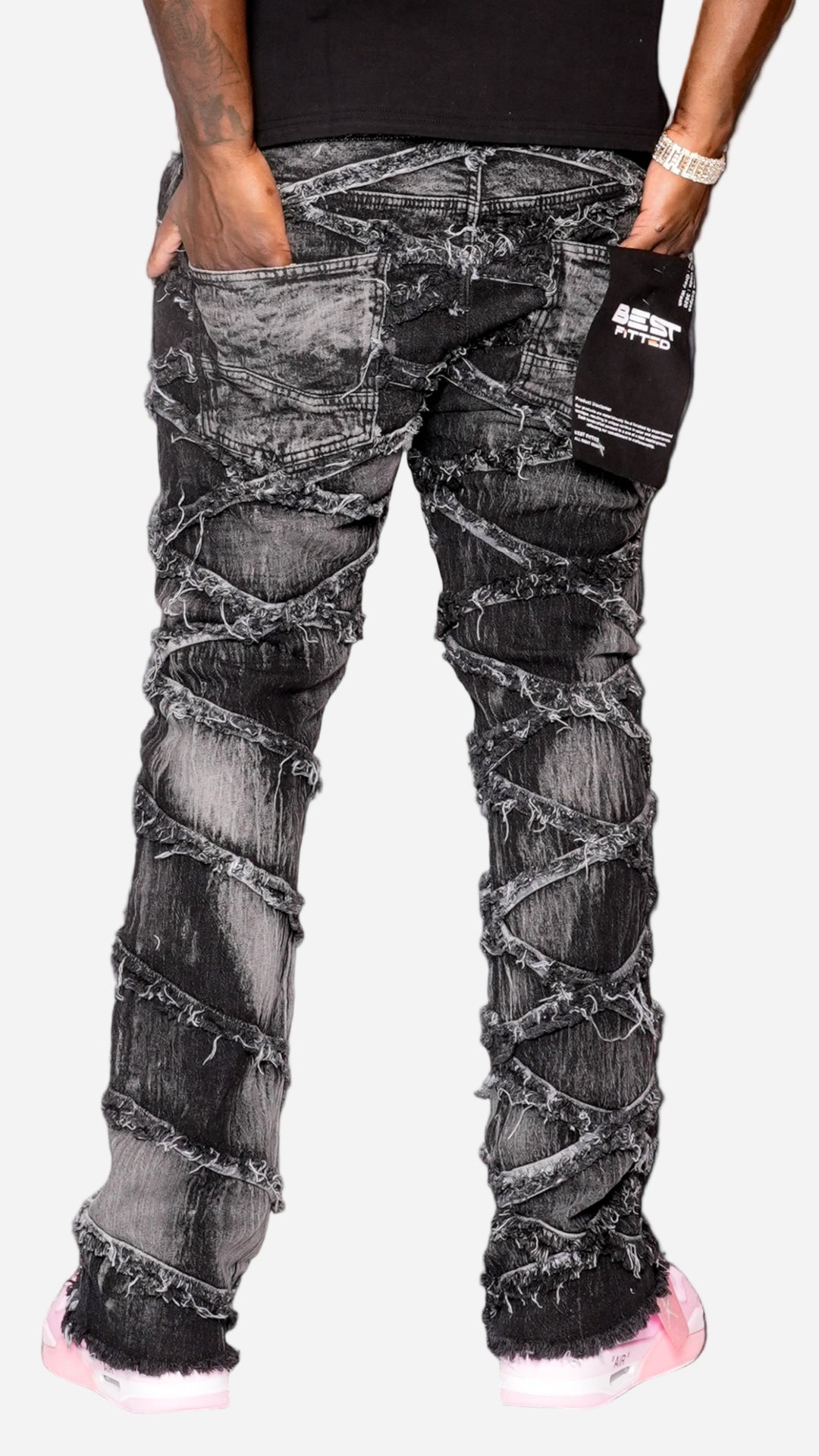 Distressed black jeans worn by a person on a gray background