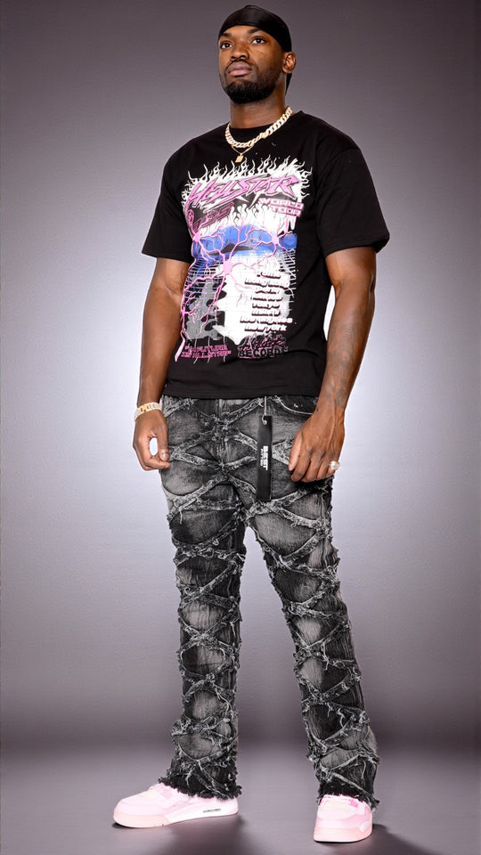 Man wearing a black graphic t-shirt and camouflage pants on a gray background