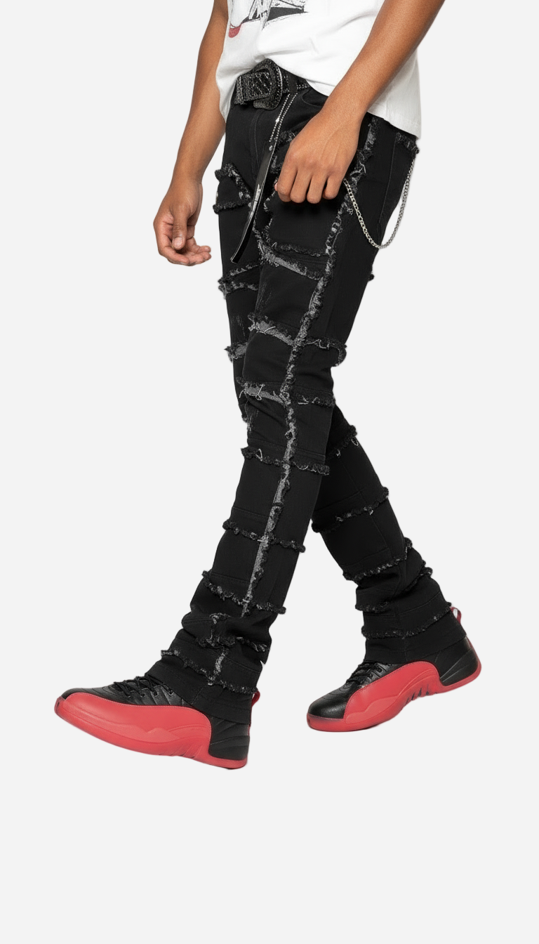 Person wearing black jeans with white stitching and red shoes on a white background