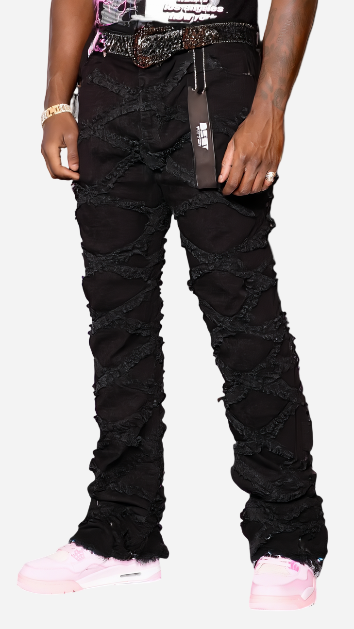 Person wearing black distressed jeans with a visible brand tag on a gray background